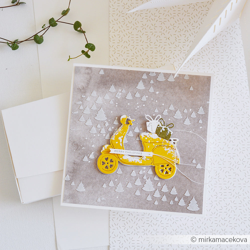 Handgefertigte Weihnachtskarte mit einer Motivstanze Herzlicher Geschenke-Roller in einem verschneiten Wald.