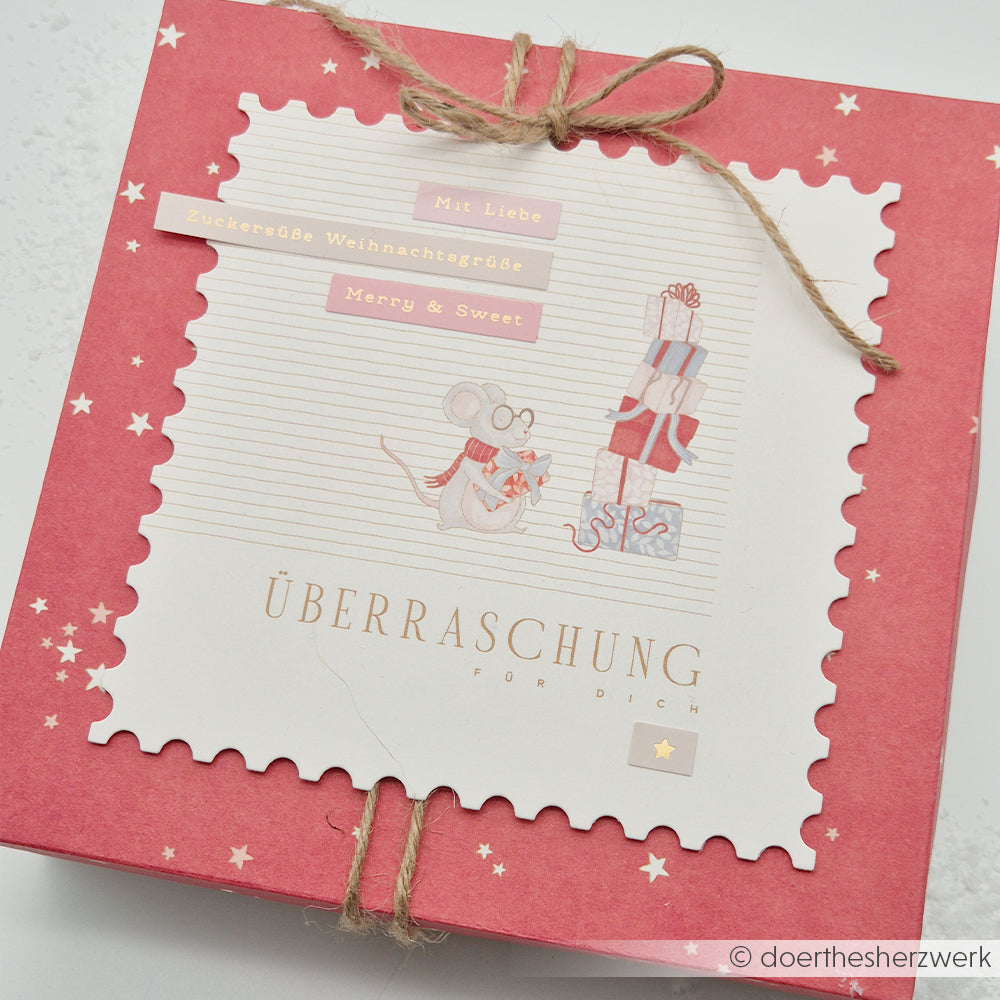Rote Geschenkbox mit einer gestanzten Karte, auf der eine Maus und ein Stapel Geschenke abgebildet sind.