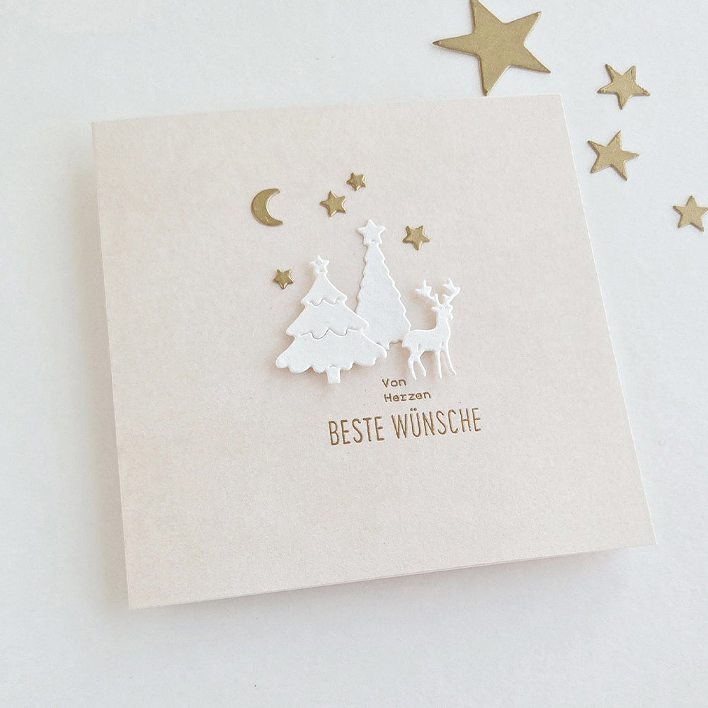 Grußkarte mit weißen, ausgestanzten Bäumen, einem Reh und goldenen Sternen sowie dem deutschen Text „Von Herzen BESTE WÜNSCHE“, gestaltet mit einer Motivstanze.