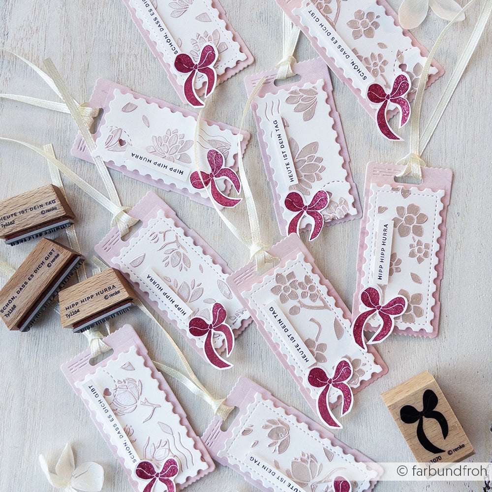 Handgefertigte Alexandra Renke-Lesezeichen mit floralen Motiven, rosafarbenen Bordüren und Schleifen - perfekt für Papierprojekte - wunderschön arrangiert auf einer hellen Holzoberfläche.