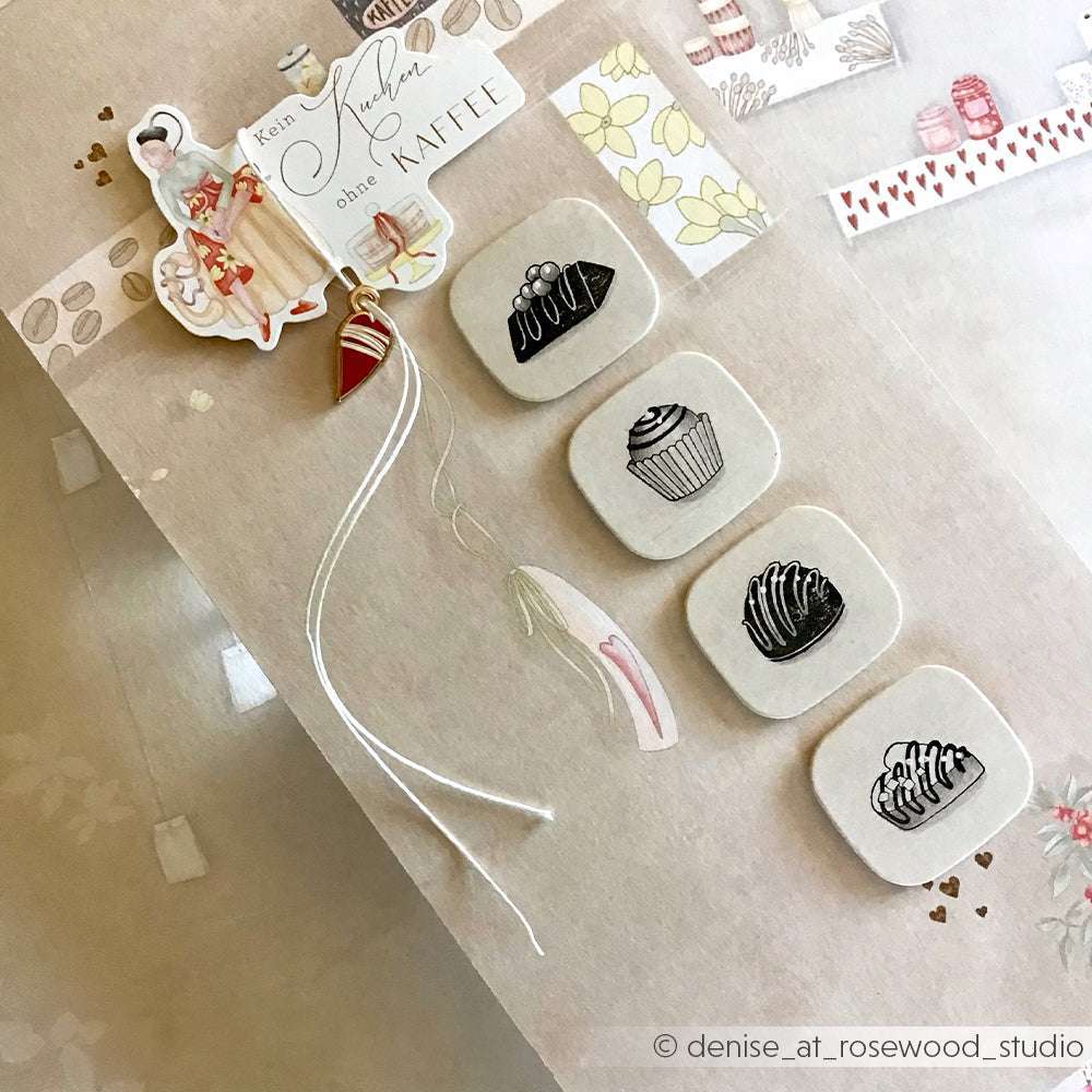 Flachdruck einer dekorativen Kaffeekarte mit Alexandra Renke Holzstempel, mit Dessertillustrationen und einem kleinen Anhänger auf beigem Hintergrund.