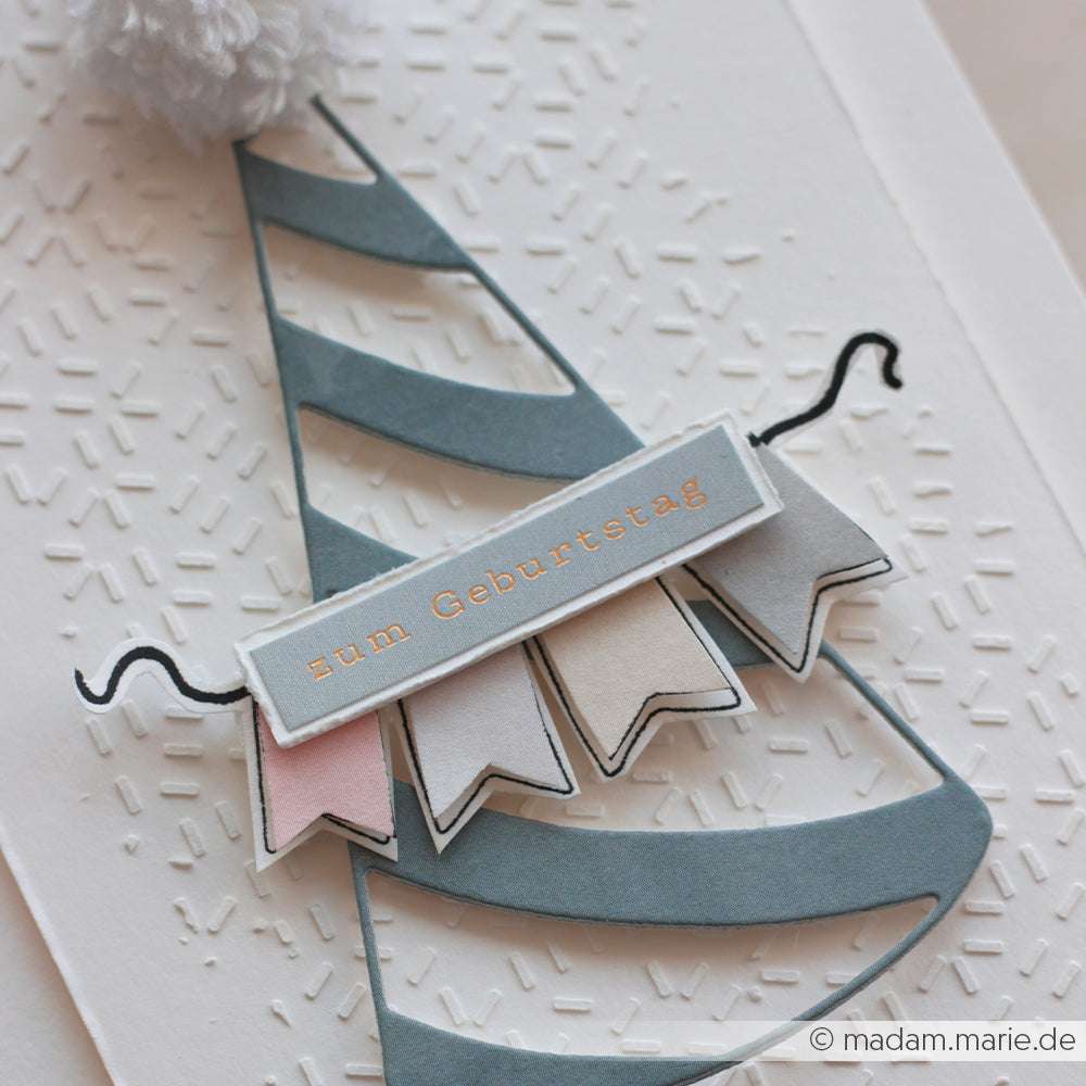 Eine Grußkarte von Alexandra Renke mit einem blauen Partyhut mit Bommel, Partyfähnchen und einem Spruchband mit der Aufschrift "zum Geburtstag".