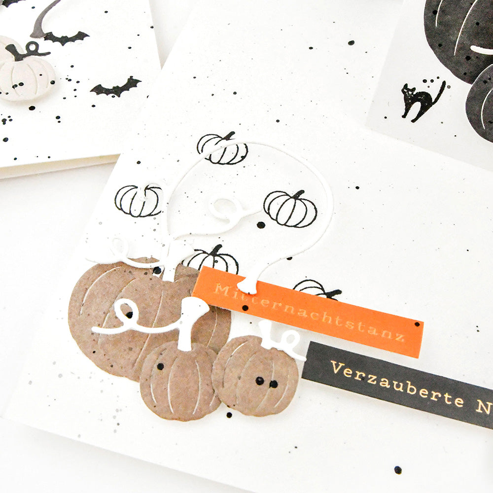 Papierkürbisse mit handgeschriebenen Anhängern, Fledermäuse aus schwarzer Tinte, gestempelt mit dem Alexandra Renke Mini Fledermaus Akzent-Stempel, und Farbspritzer auf weißem Hintergrund.