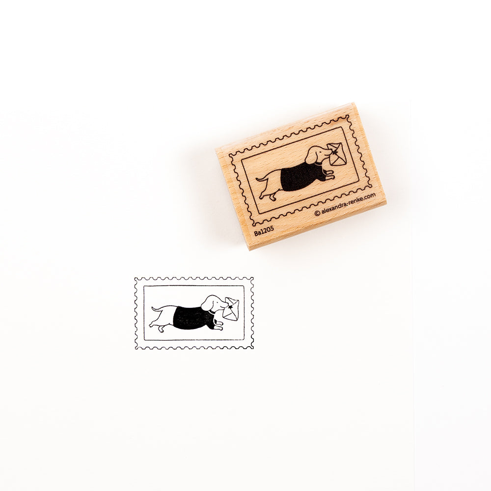 Ein Holzstempel der Marke „Dackelpost“ mit der Abbildung eines Dackels, der einen Brief trägt; unten ist das Stempelbild zu sehen.