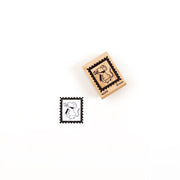 Ein Holzstempel von „Mäusepost“ mit der Abbildung einer Maus in Mantel und Schal, daneben der Stempelabdruck.