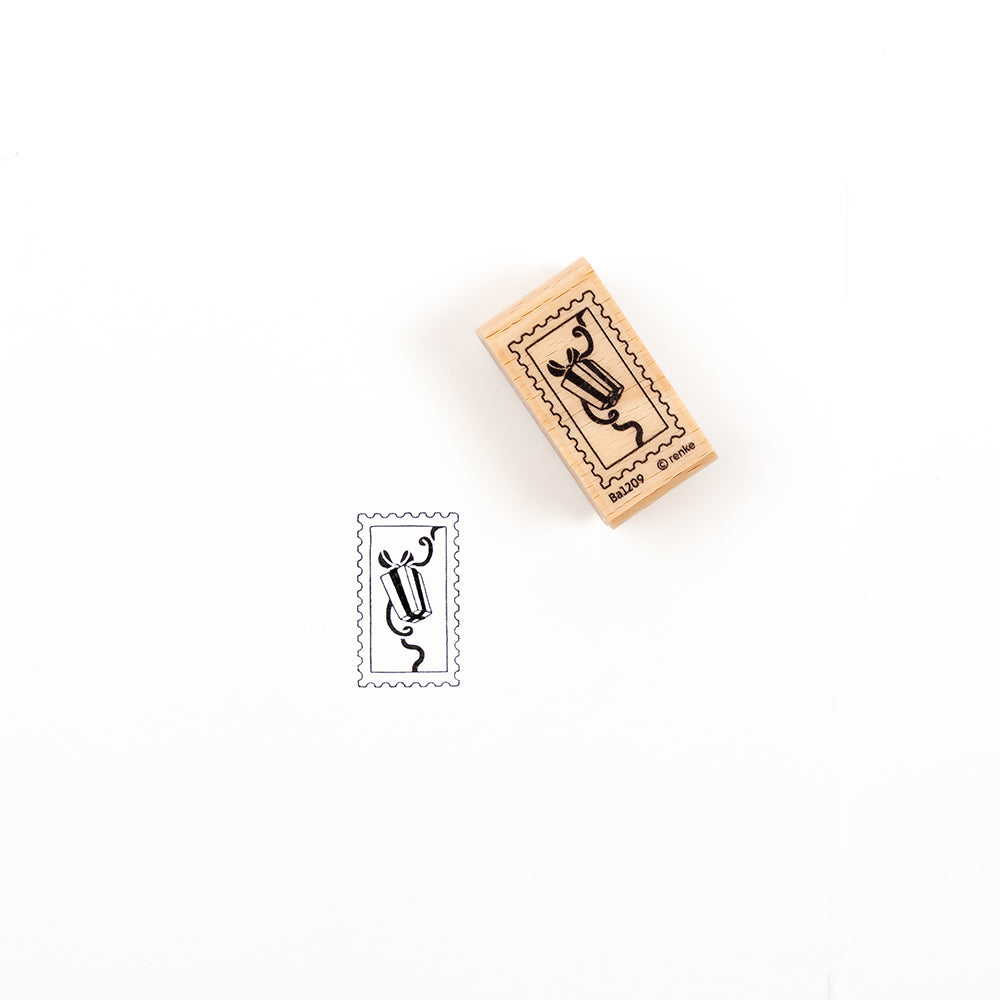 Ein Holzstempel mit einem Geschenkbox-Motiv neben dem Stempelabdruck.