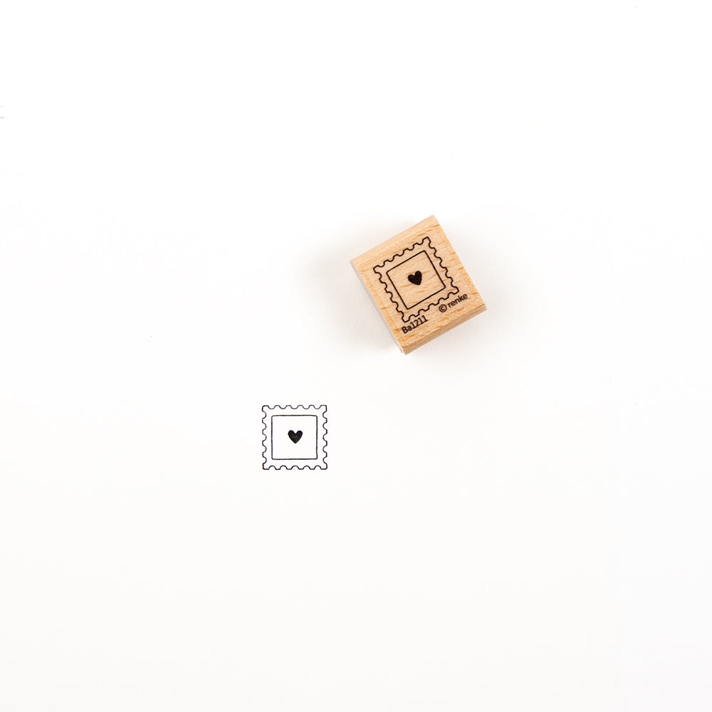 Ein Holzstempel mit Herzmotiv und dem dazugehörigen Abdruck in schwarzer Tinte.