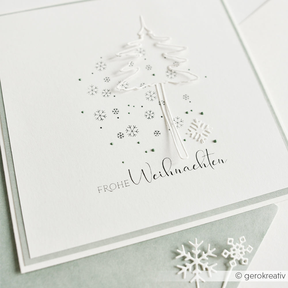 Weiße Weihnachtskarte mit einem Drahtbaum, Schneeflocken und einem Sternenhintergrund, auf der FROHE Weihnachten steht.