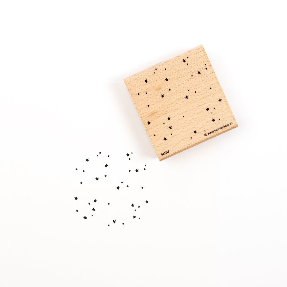 Ein auf Holz montierter Stempelgummi mit einem Sternenfeldmuster und einem Muster des Motivs, das darunter abgestempelt ist.