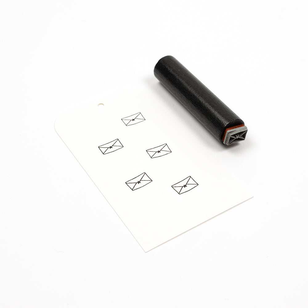 Ein schwarzer Holzstempel neben einem Anhänger mit fünf gestempelten „Mini-Brief mit Stern“-Symbolen.