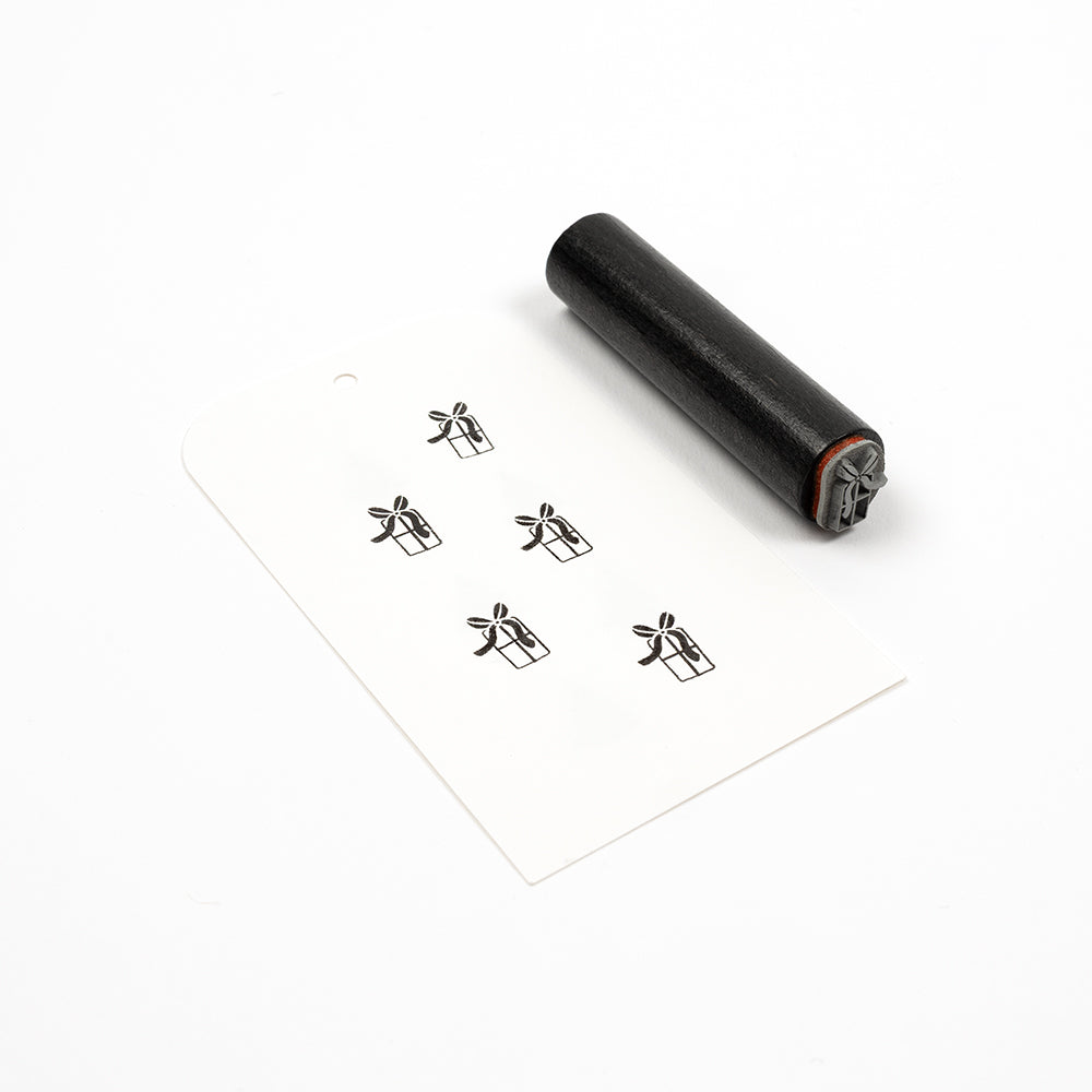 Ein Akzentstempel aus Gummi und ein Geschenkanhänger, auf dem fünf Geschenkbox-Symbole aufgestempelt sind.