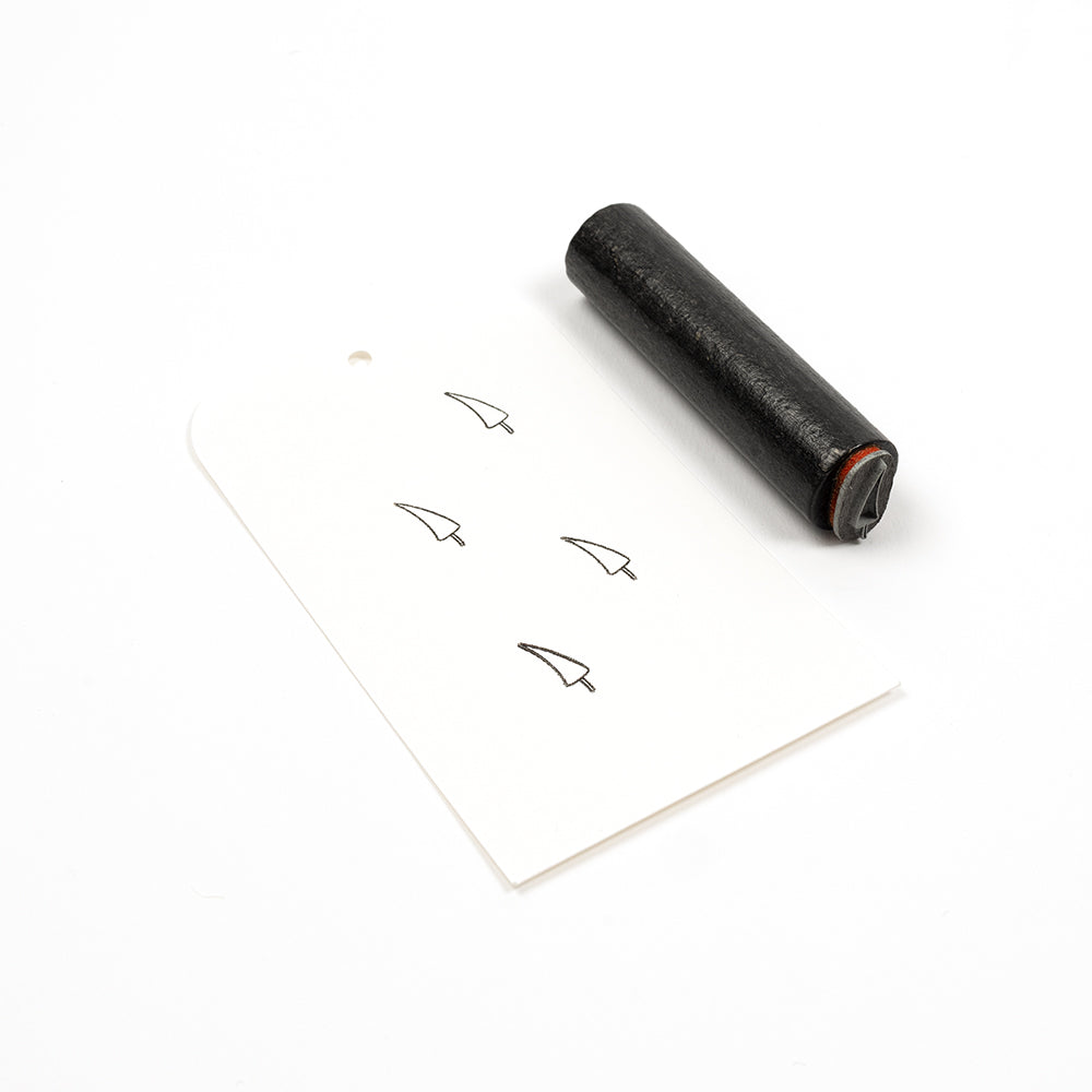Ein schwarzer Holzstempel und eine Karte, auf der vier kleine Chilischoten-Symbole aufgestempelt sind.
