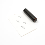 Ein schwarzer Holzstempel und eine Karte, auf der vier kleine Chilischoten-Symbole aufgestempelt sind.
