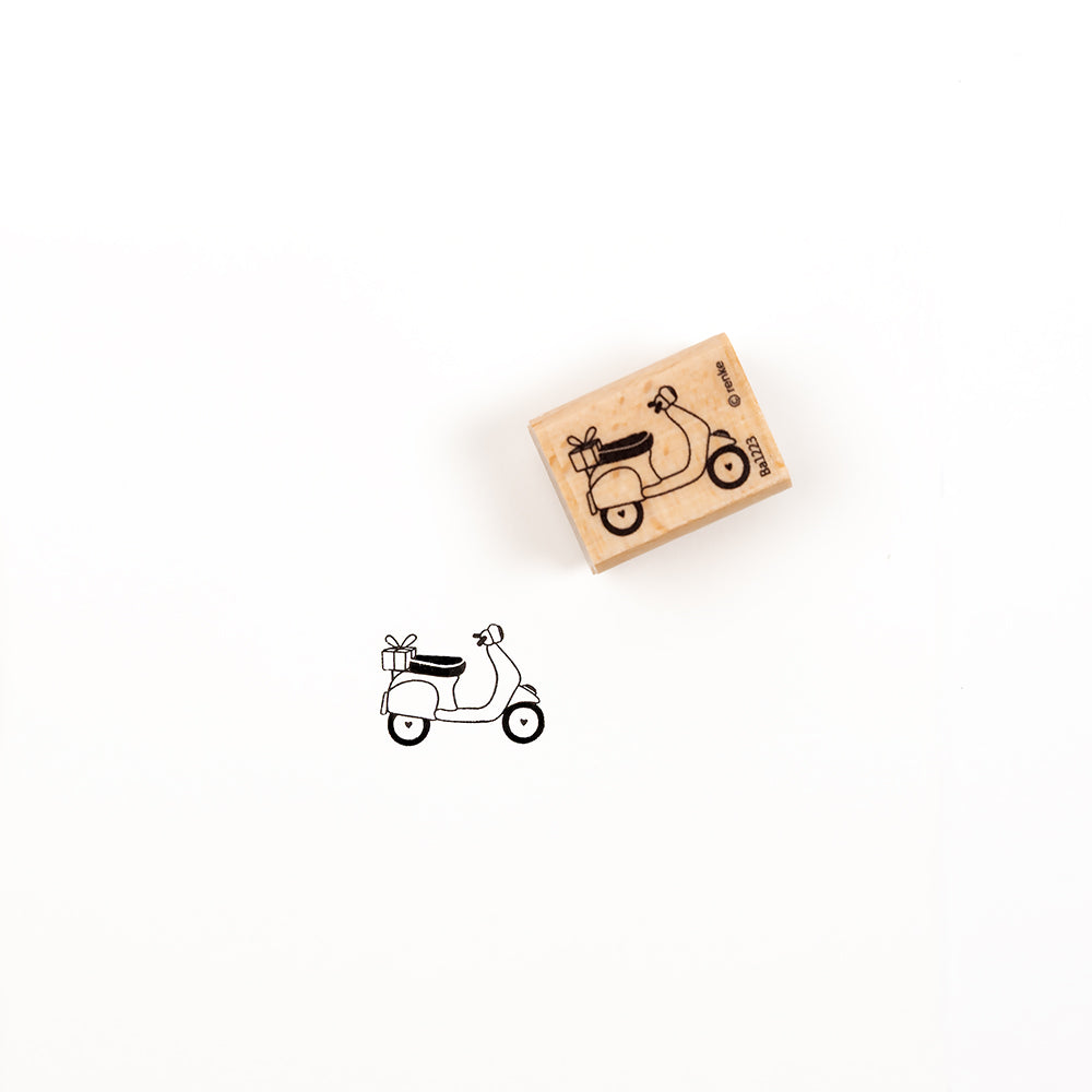 Ein Holzstempel mit der Abbildung eines Geschenkerollers, auf dessen Rückseite ein Geschenk zu sehen ist, dargestellt mit einem Stempelabdruck desselben Motivs.
