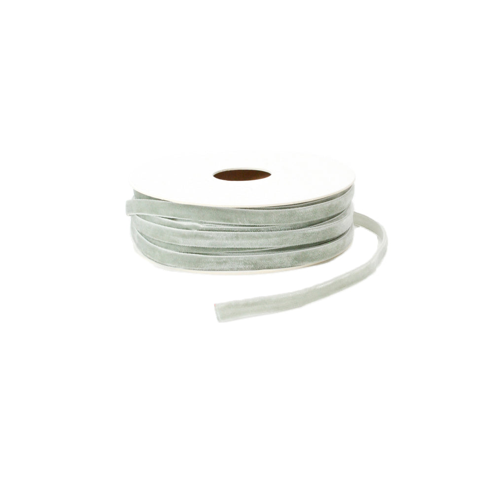 Eine Spule hellgrünes Samtband von Vivant Decorations BV, mit einem Ende seitlich abfallend, vor weißem Hintergrund.