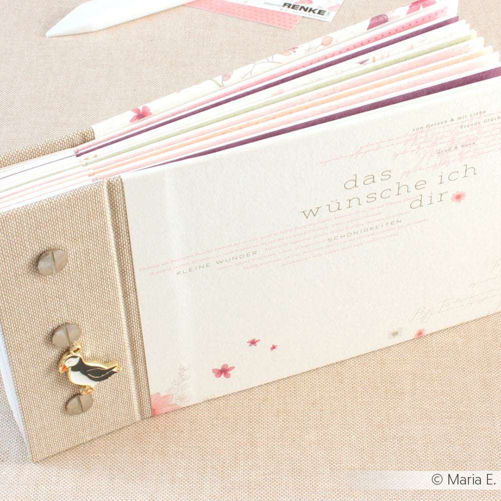 Ein beiges und rosafarbenes Sammelalbum der Marke ☆ mit deutschem Text und einem Storchenanhänger auf dem Buchleineneinband, abgebildet auf einem hellen Hintergrund.