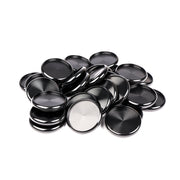 Ein Stapel blanker, runder, schwarzer und silberner Metallknöpfe von Alexandra Renke, die üblicherweise als Bindescheiben für die Buchbinderei verwendet werden, angeordnet auf einem weißen Hintergrund.