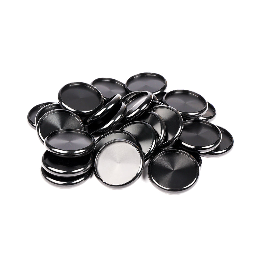 Ein Stapel blanker, runder, schwarzer und silberner Metallknöpfe von Alexandra Renke, die üblicherweise als Bindescheiben für die Buchbinderei verwendet werden, angeordnet auf einem weißen Hintergrund.