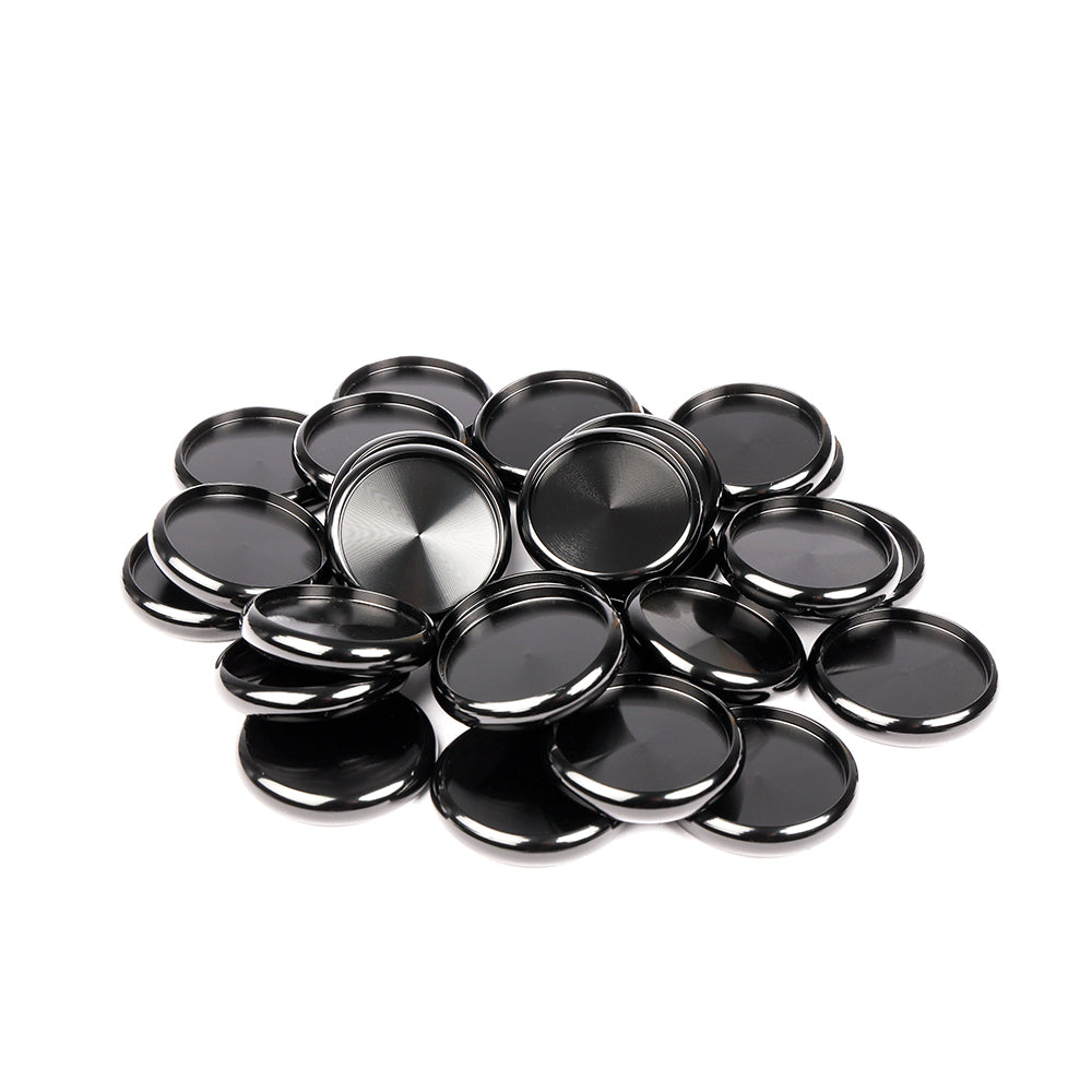Ein Stapel glänzender, runder Bindescheiben (Kappen) aus schwarzem Metall von Alexandra Renke auf weißem Hintergrund, wesentliche Bindeelemente, die oft für Buchbinden verwendet werden.