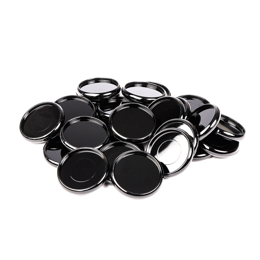 Ein Stapel glänzender, schwarzer Alexandra-Renke-Deckel mit silbernem Rand - ähnlich wie Bindescheiben - liegt auf einem weißen Hintergrund.