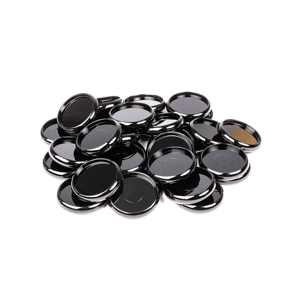 Ein Stapel glänzender, runder schwarzer Alexandra Renke Bindescheiben auf weißem Hintergrund.