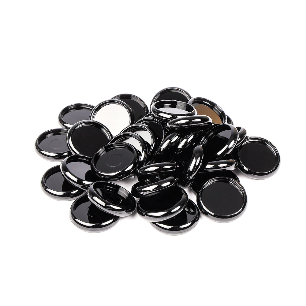 Ein Haufen glänzender schwarzer und silberner Alexandra Renke Flaschenverschlüsse, perfekt als einzigartige Bindeelemente für Ihr nächstes Mini-Album, verstreut auf einem weißen Hintergrund.