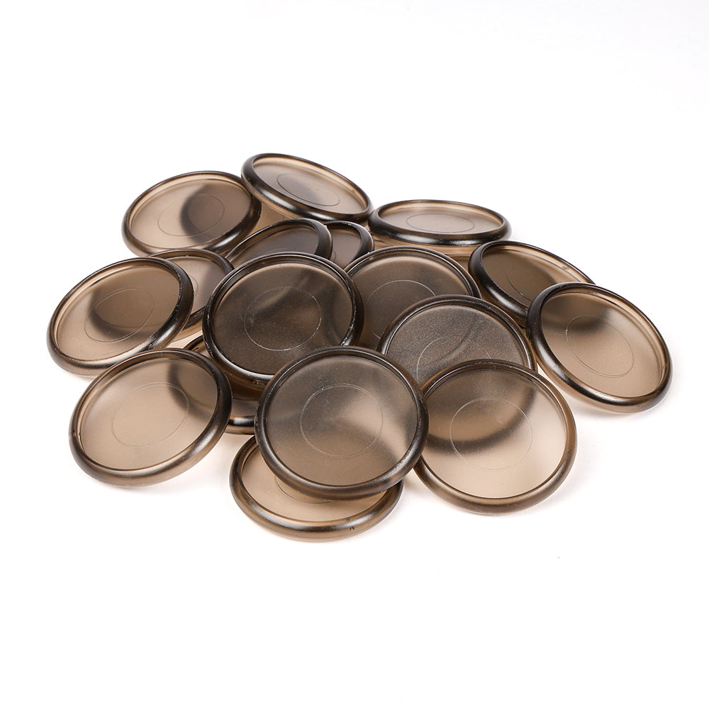 Ein Stapel runder, durchscheinender brauner Alexandra Renke Bindescheiben, ideal zum Buchbinden, verstreut auf einer weißen Fläche.