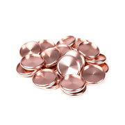 Ein Stapel glänzender, runder, roségoldener Metallscheiben von Alexandra Renke auf weißem Hintergrund.