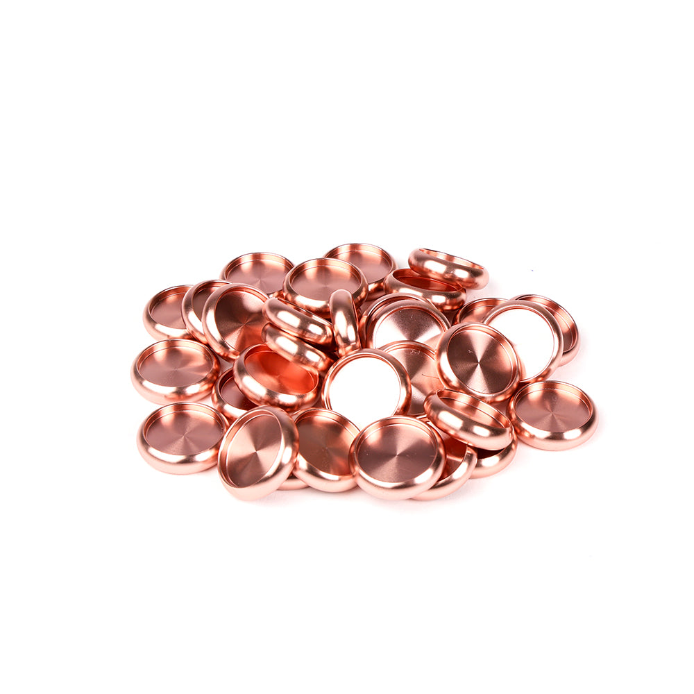 Ein Stapel glänzender kupferfarbener Alexandra Renke Bindescheiben Metallkappen auf einem weißen Hintergrund.