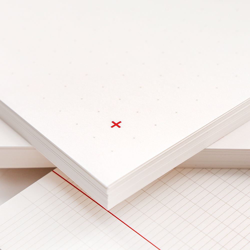 Stapel weißer Millimeterpapiere mit hellen Punkten und einem kleinen roten X in der unteren Ecke, entworfen als lose Blätter für Ihren Notizblock von Alexandra Renke.