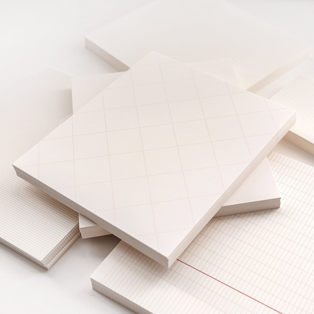 Stapel von leeren Alexandra Renke Notizblöcken und losen Blättern mit verschiedenen Raster-, Linien- und Punktmustern - ideal für Bullet-Journal-Setups - auf weißem Hintergrund angeordnet.