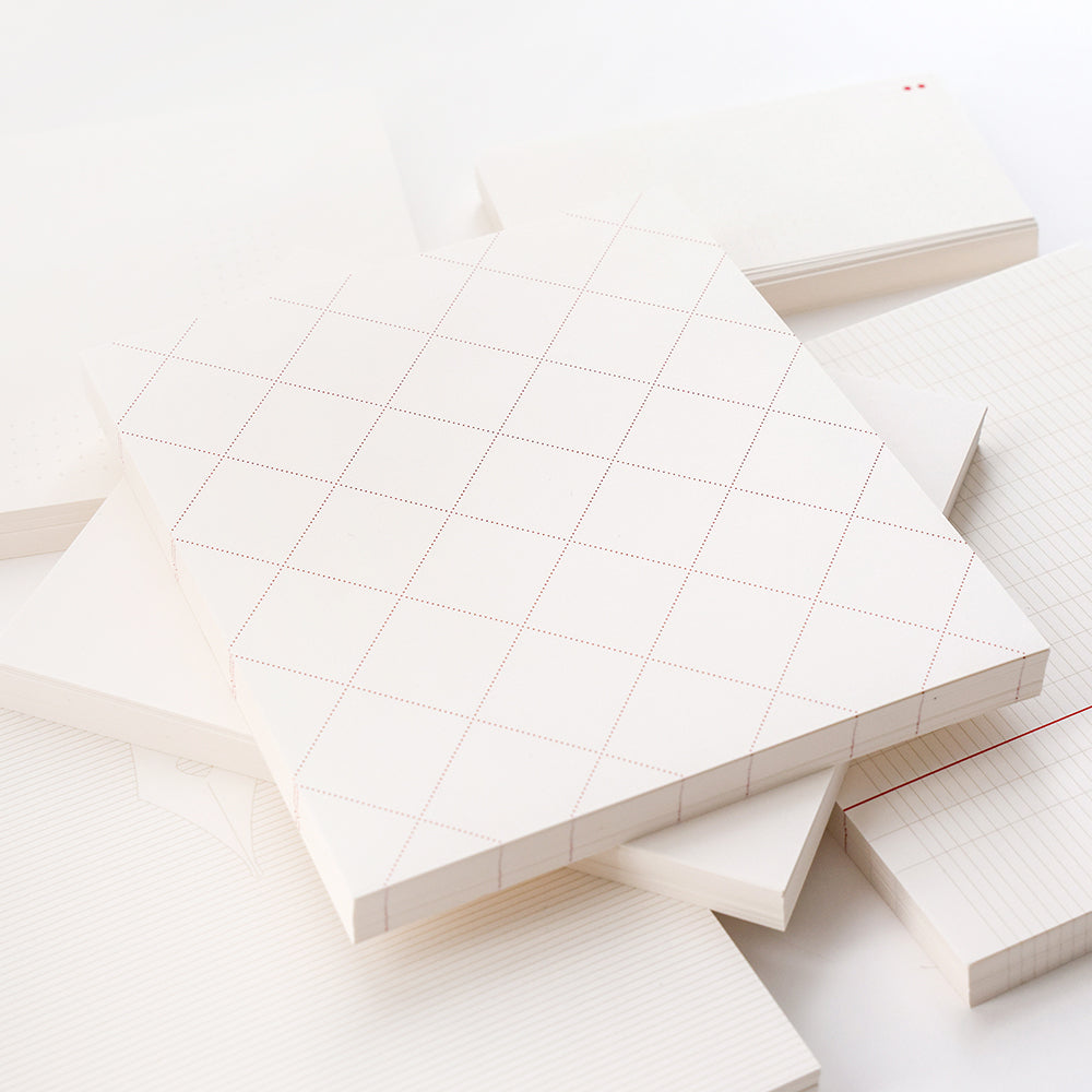 Ein ordentlich geordneter Stapel von Alexandra Renke Notizblöcken und losen Blättern mit subtilen Gitter-, Punkt- und Linienmustern auf den Einbänden - perfekt für Bullet-Journal-Liebhaber.