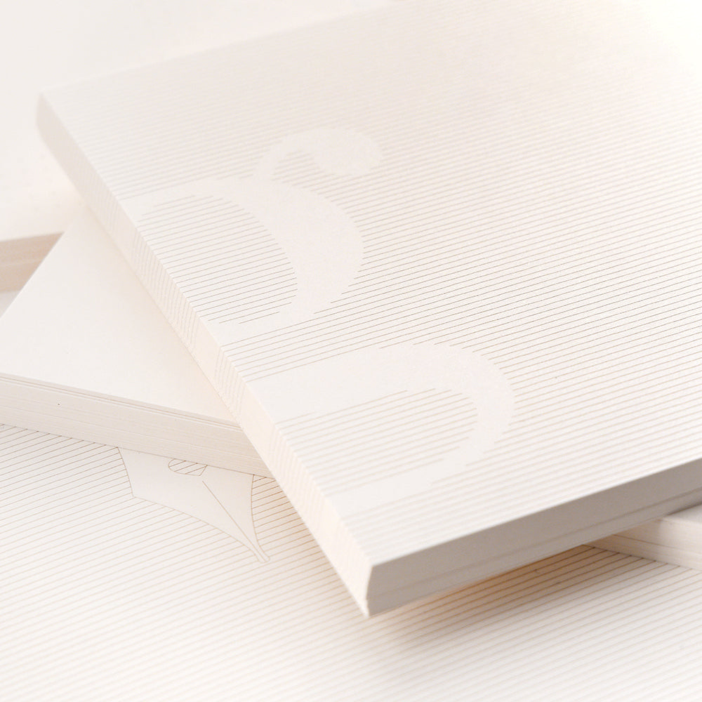 Eine Nahaufnahme von drei gestapelten, weißen, strukturierten Alexandra Renke Bullet-Journal-Notizbüchern mit dezenten Prägungen und linierten Einbänden.