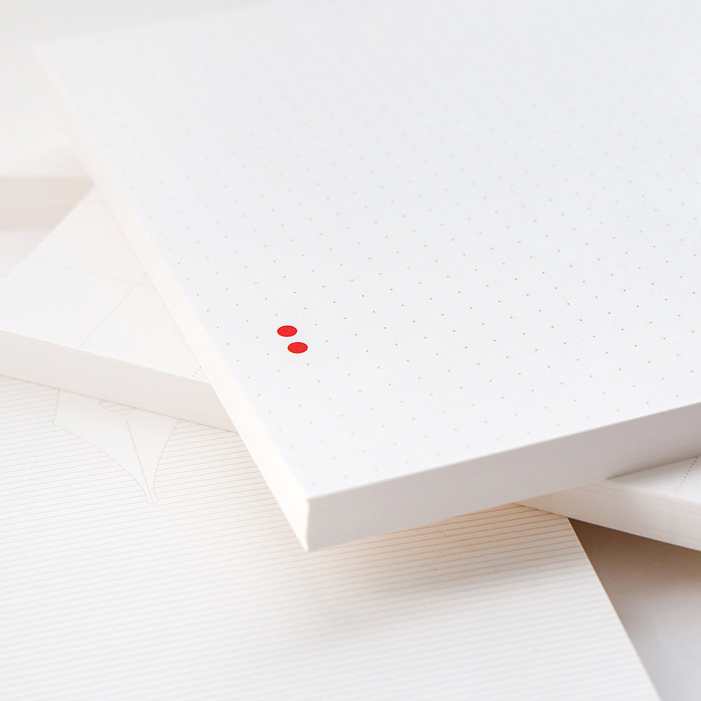 Der weiß gepunktete Notizblock von Alexandra Renke hat zwei kleine rote Punkte auf dem Cover und lässt sich auf linierten und unlinierten Notizbüchern stapeln - perfekt für Bullet-Journal-Fans oder zum Organisieren loser Blätter.