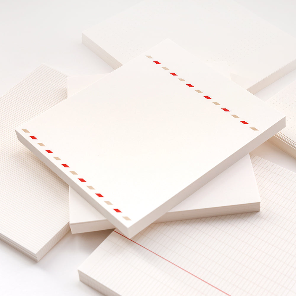 Stapel von Alexandra Renke Notizblöcken mit verschiedenen Linienmustern; der oberste Block hat einen roten und grauen diagonalen Streifenrand - ideal für Bullet-Journal-Fans oder zum Ordnen loser Blätter.