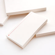 Ein Stapel leerer, linierter Karteikarten von Alexandra Renke mit einer roten Randlinie, umgeben von anderen Notizblöcken und losen Blättern auf einer weißen Fläche.