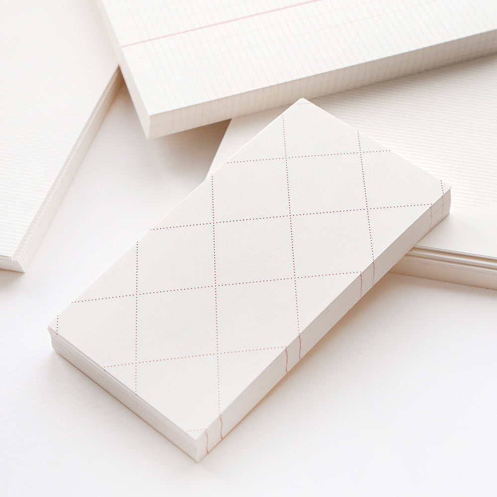 Ein Stapel rechteckiger Alexandra Renke Notizblöcke und loser Blätter mit Raster- und Linienmustern auf weißem Papier - ideal für Ihr Bullet Journal - schön auf einer weißen Unterlage angeordnet.