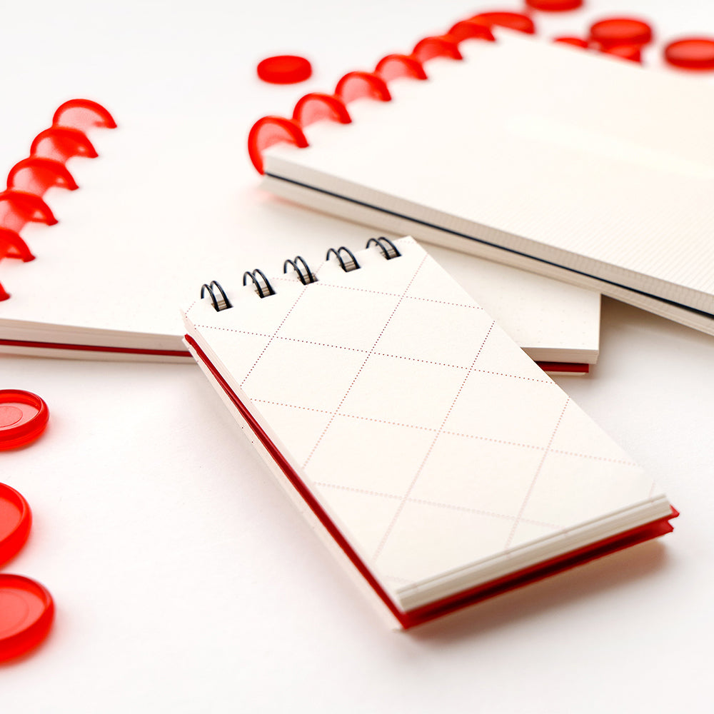Drei Notizblöcke von Alexandra Renke mit roter Spiralbindung und roten Discs liegen auf einer weißen Fläche - perfekt als Bullet-Journal oder für lose Blätter.