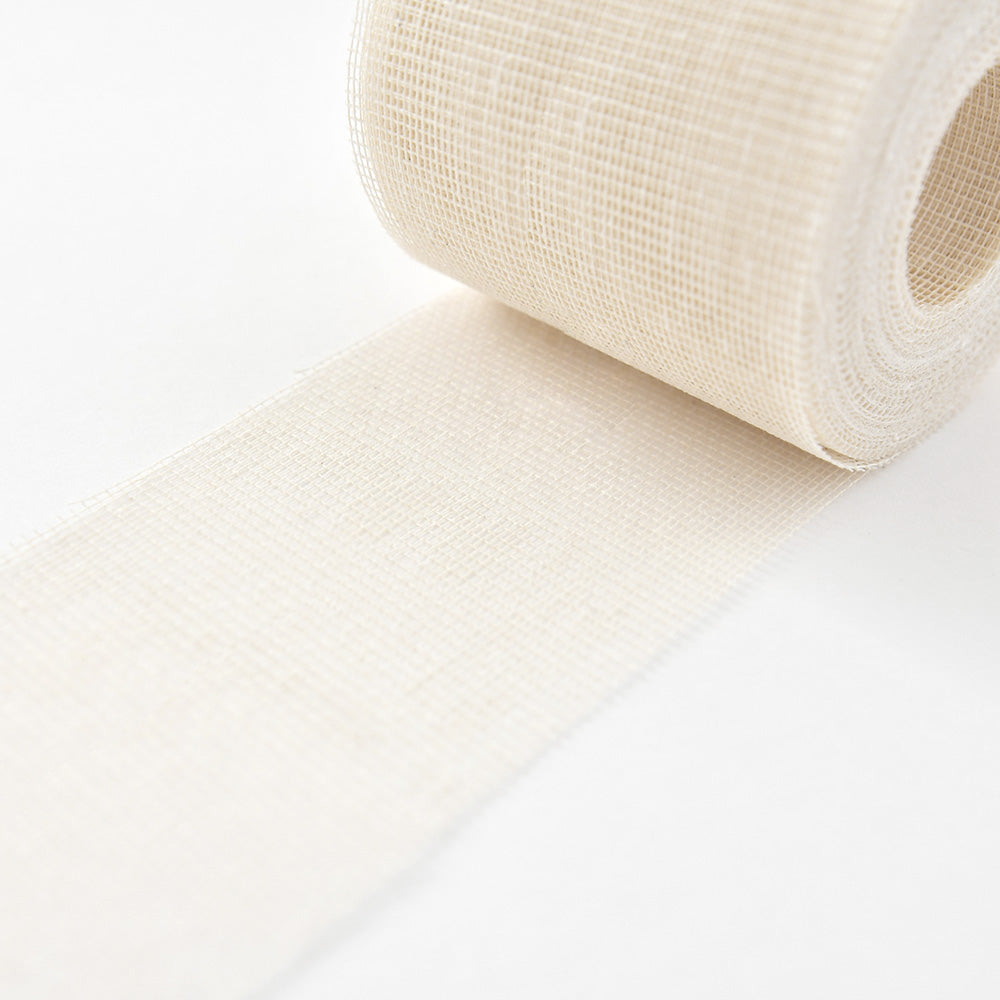 Nahaufnahme einer Rolle weißen ☆ medizinischen Verbandsmaterials (Heftgaze), das auf einer weißen Fläche abgerollt wird.