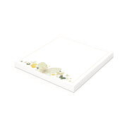 Ein weißer Notizblock von Alexandra Renke mit einem zarten Schmetterlingsreigen aus hochwertigem Papier und einem Blattmotiv in einer Ecke auf einem schlichten Hintergrund.