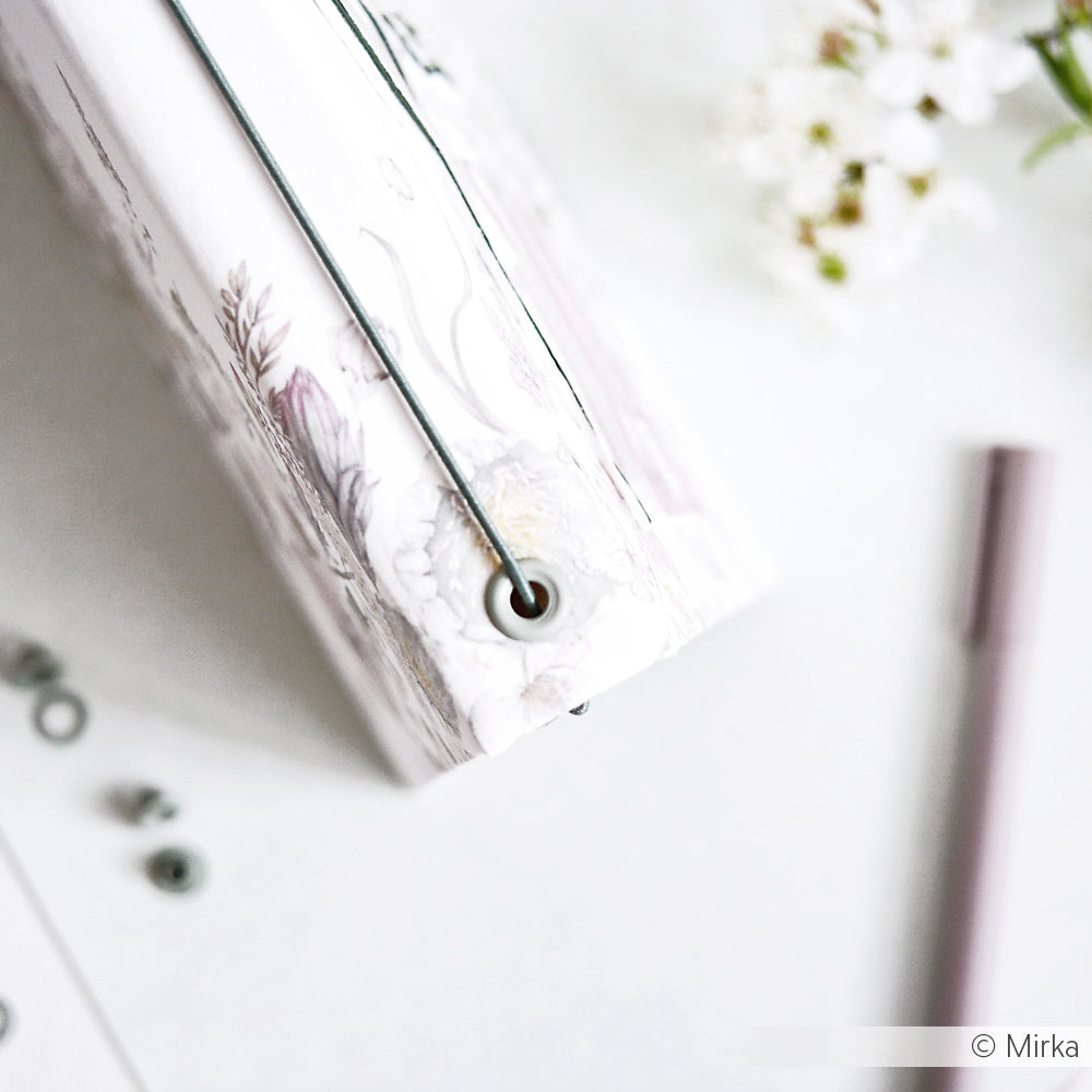 Eine elegante Blumenmappe Jaspisgrün von Alexandra Renke mit Ösen mit Unterlegscheibe, Gummiband, Stifthalter und zarten weißen Blumen auf hellem Grund.