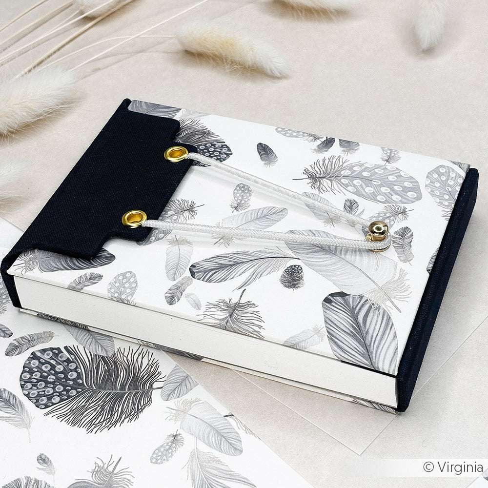 Eine dekorative Dokumentenmappe von Alexandra Renke mit federgemusterten Designpapieren und einer schwarzen Klappe mit Kordel- und Knopfverschluss - ideal für kreatives Buchbinden oder als einzigartiges Bucheinbandpapier.