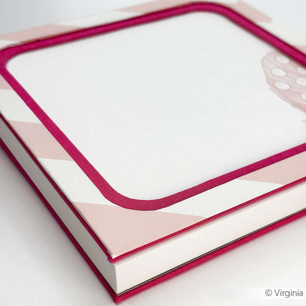 Eine Nahaufnahme eines Alexandra Renke Hardcover-Notizbuchs mit einem rosa Blockstreifen Rosa Rand und leeren weißen Seiten, mit elegantem Bucheinbandpapier.