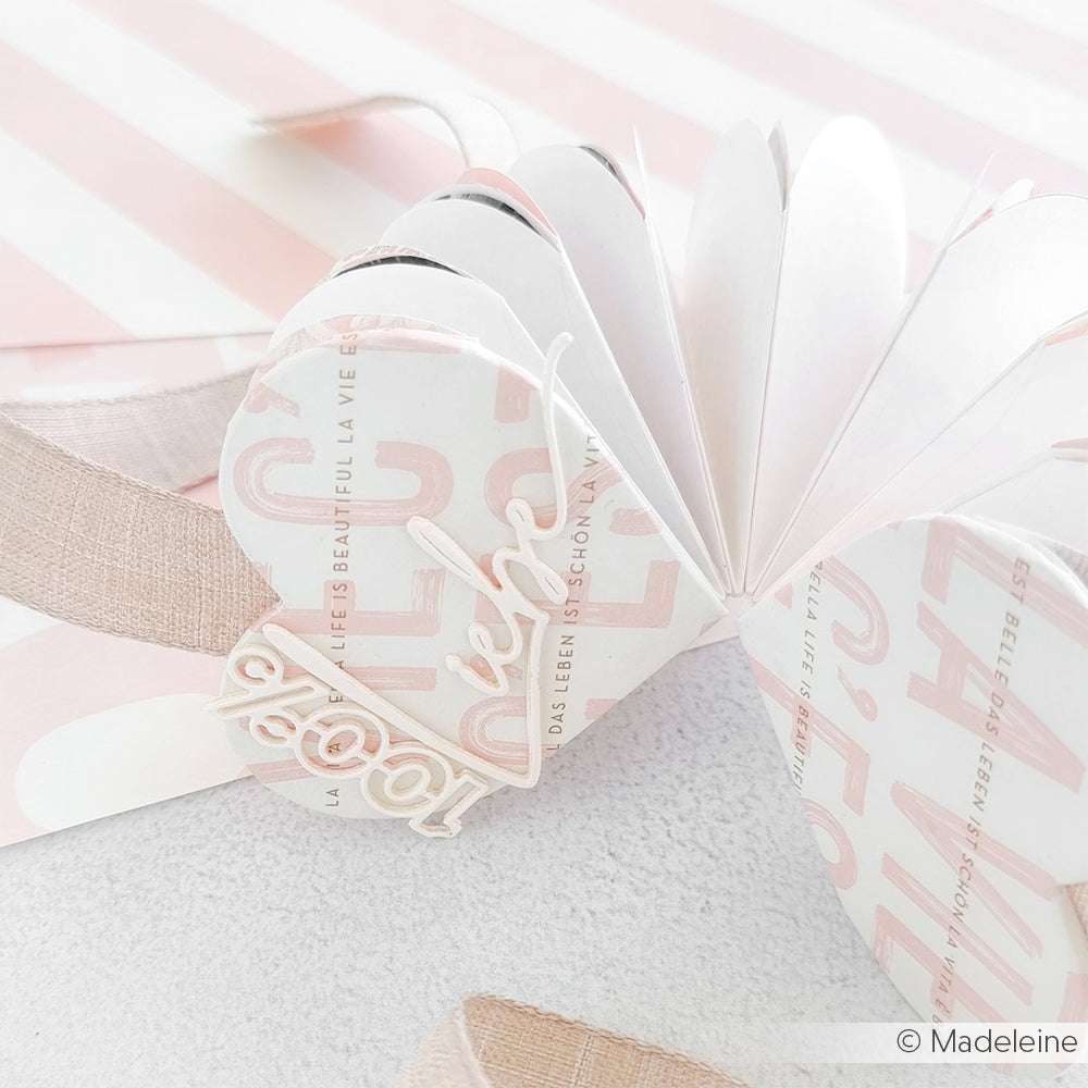 Herzförmige Akkordeonkarte von Alexandra Renke, gestaltet mit rosa und weißem Designpapier, zarten Textakzenten und einer bezaubernden Liebesverzierung obenauf.