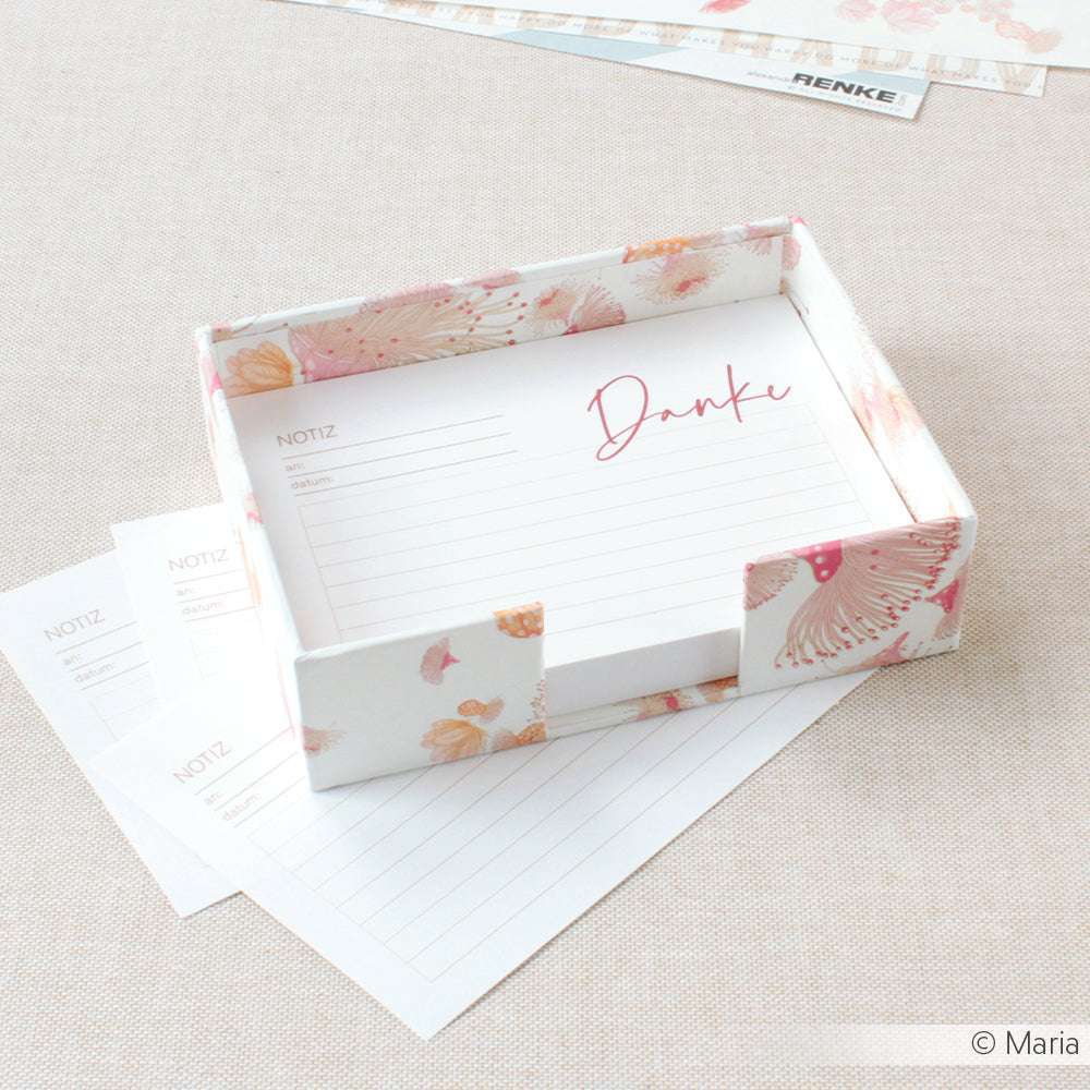 Die geblümte Notizkartenbox von Alexandra Renke mit dem Schriftzug "Danke" auf dem Deckel ist aus elegantem Designpapier gefertigt und bietet Platz für gefütterte Notizzettel, neben denen weitere Blätter platziert werden können.