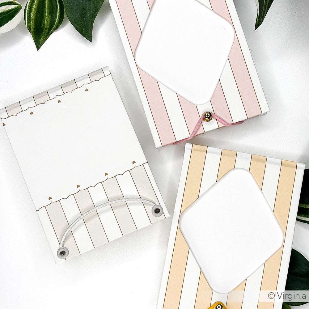 Drei gestreifte Notizblöcke von Alexandra Renke, gefertigt aus hochwertigem Designpapier mit dekorativen Ausschnitten, dargestellt auf einer weißen Fläche und akzentuiert durch grüne Blätter in den Ecken.