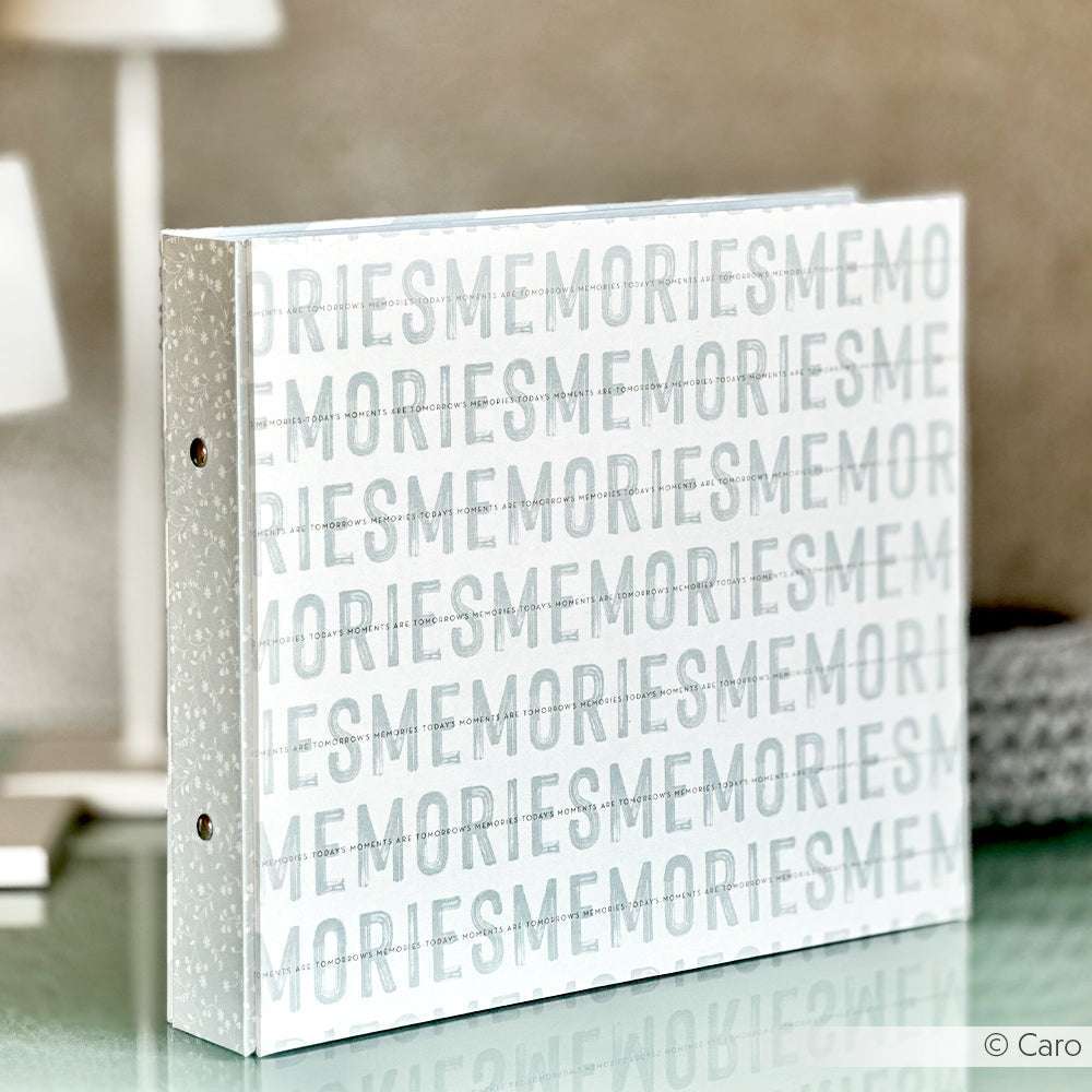 Alexandra Renke weißes Fotoalbum mit "MEMORIES" in silbernen Lettern auf dem Einband, stehend auf Glas. Gefertigt mit hochwertigem Bucheinbandpapier für ein edles Finish.