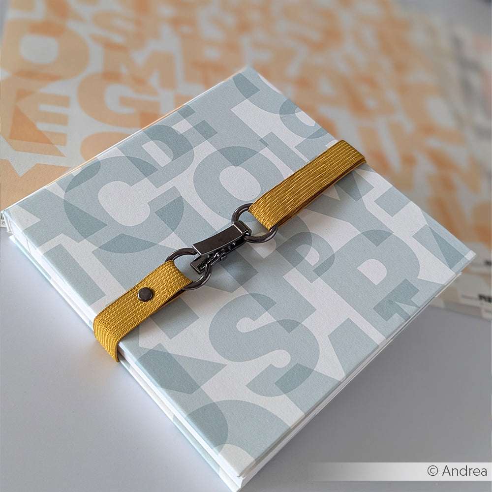 Das Buch von Alexandra Renke zeichnet sich durch große Buchstaben auf dem Einband, einen gelben Riemen mit Metallschließe zum Verschließen und einzigartiges Bucheinbandpapier für eine kreative Note aus.