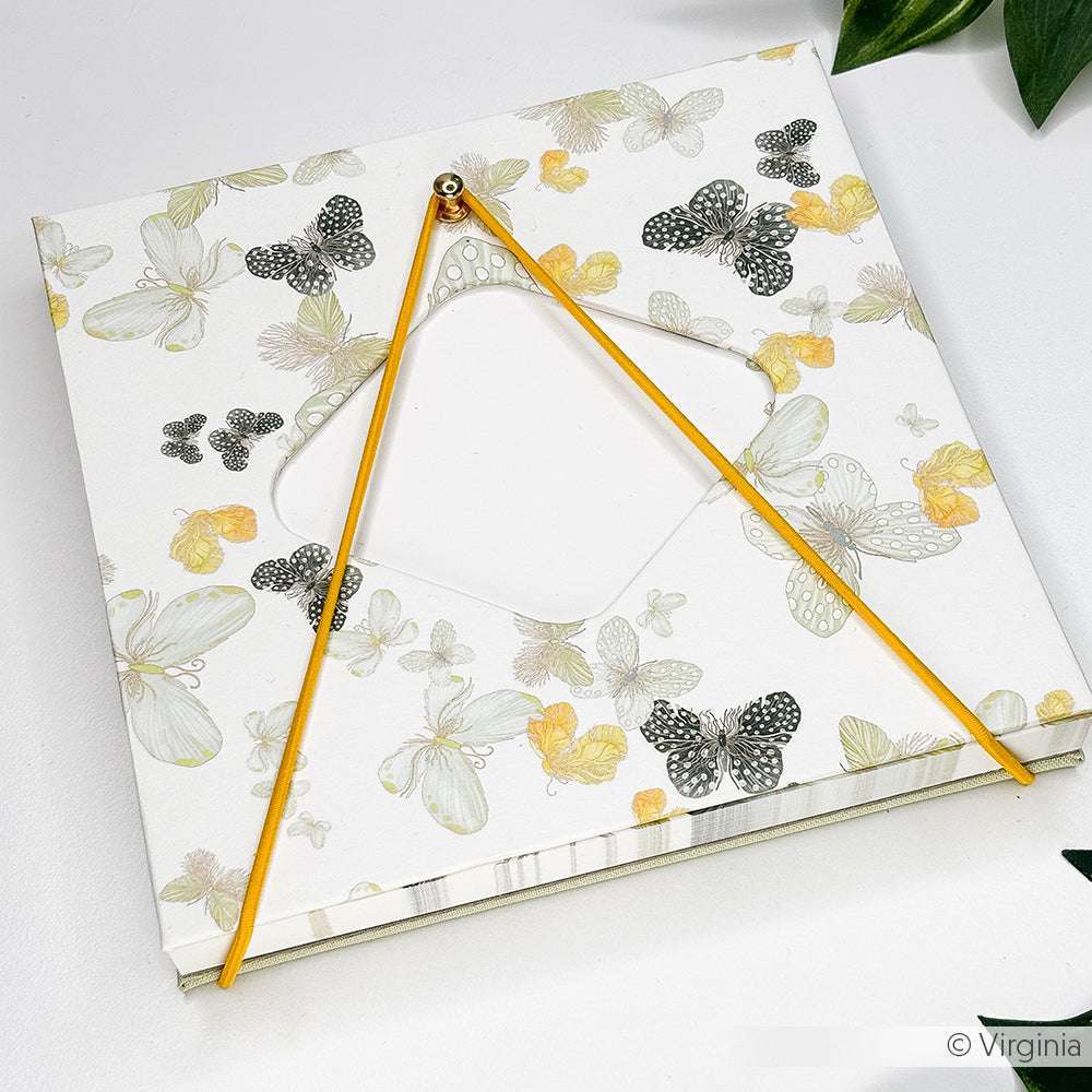 Ein Notizbuch von Alexandra Renke mit Schmetterling Designpapier mit zwei gelben Stiften im Dreieck - ideal für Buchbinden-Liebhaber, die kreative Inspiration suchen.