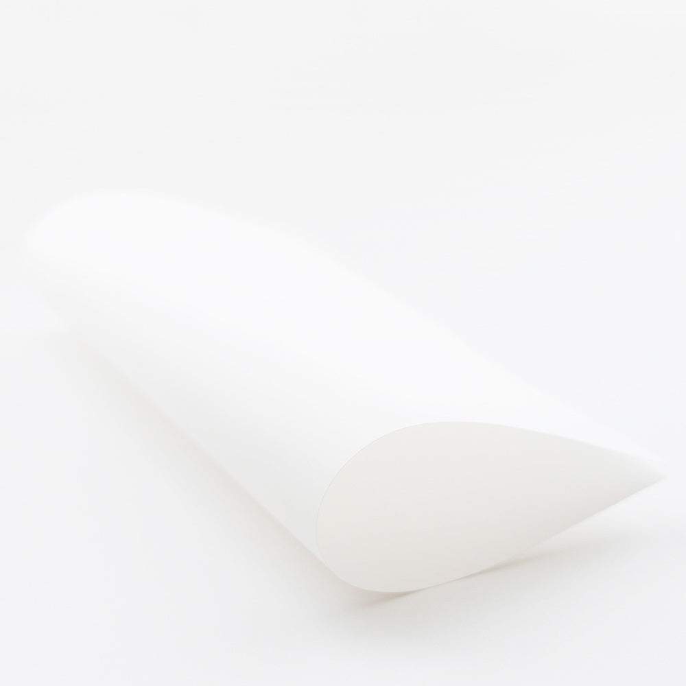 Ein einzelnes Blatt 120 g/m² weißes Bucheinbandpapier von Alexandra Renke, teilweise gerollt auf weißem Untergrund.